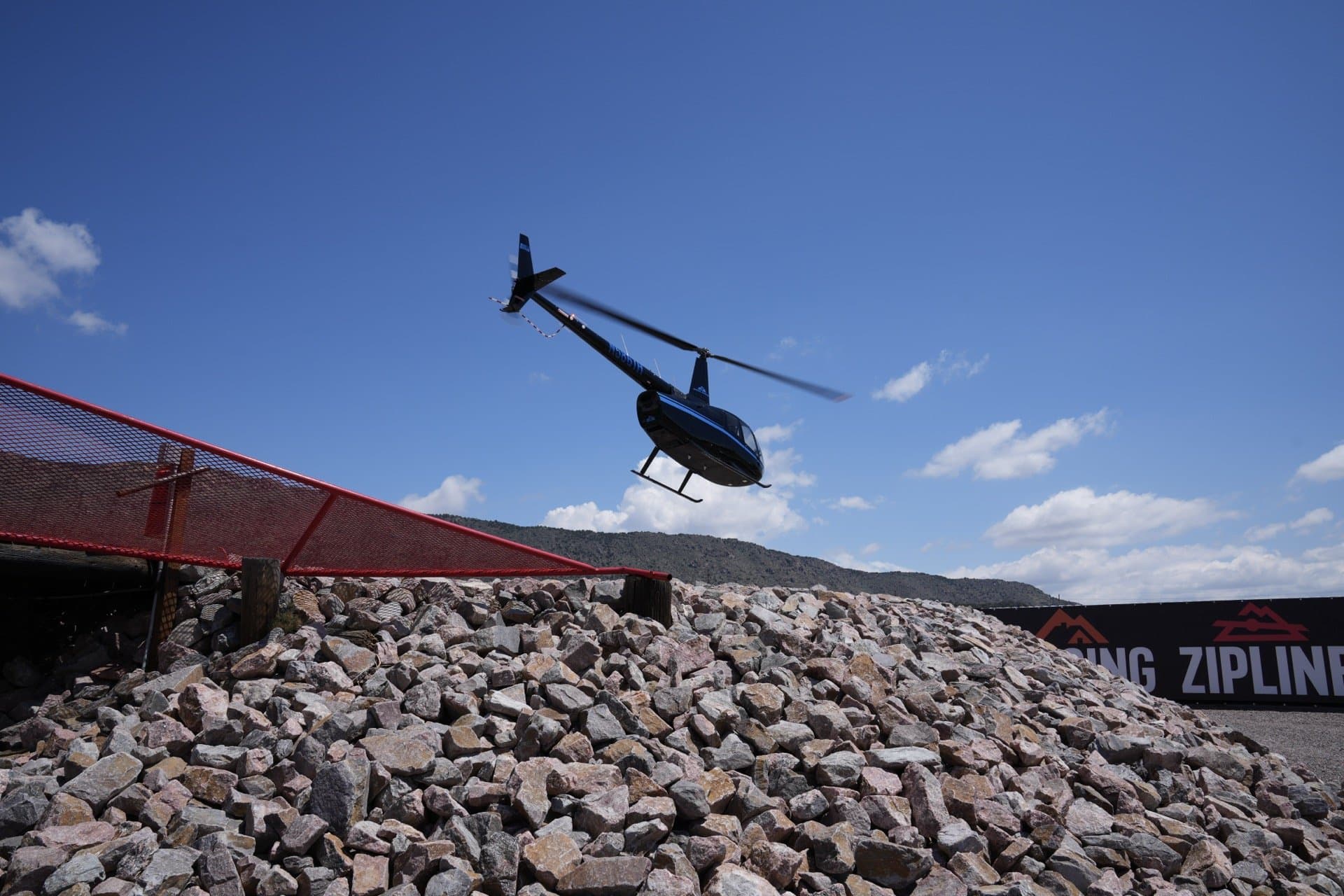 Helicopter lifting off from the helipad with ZIPLINE signage in background