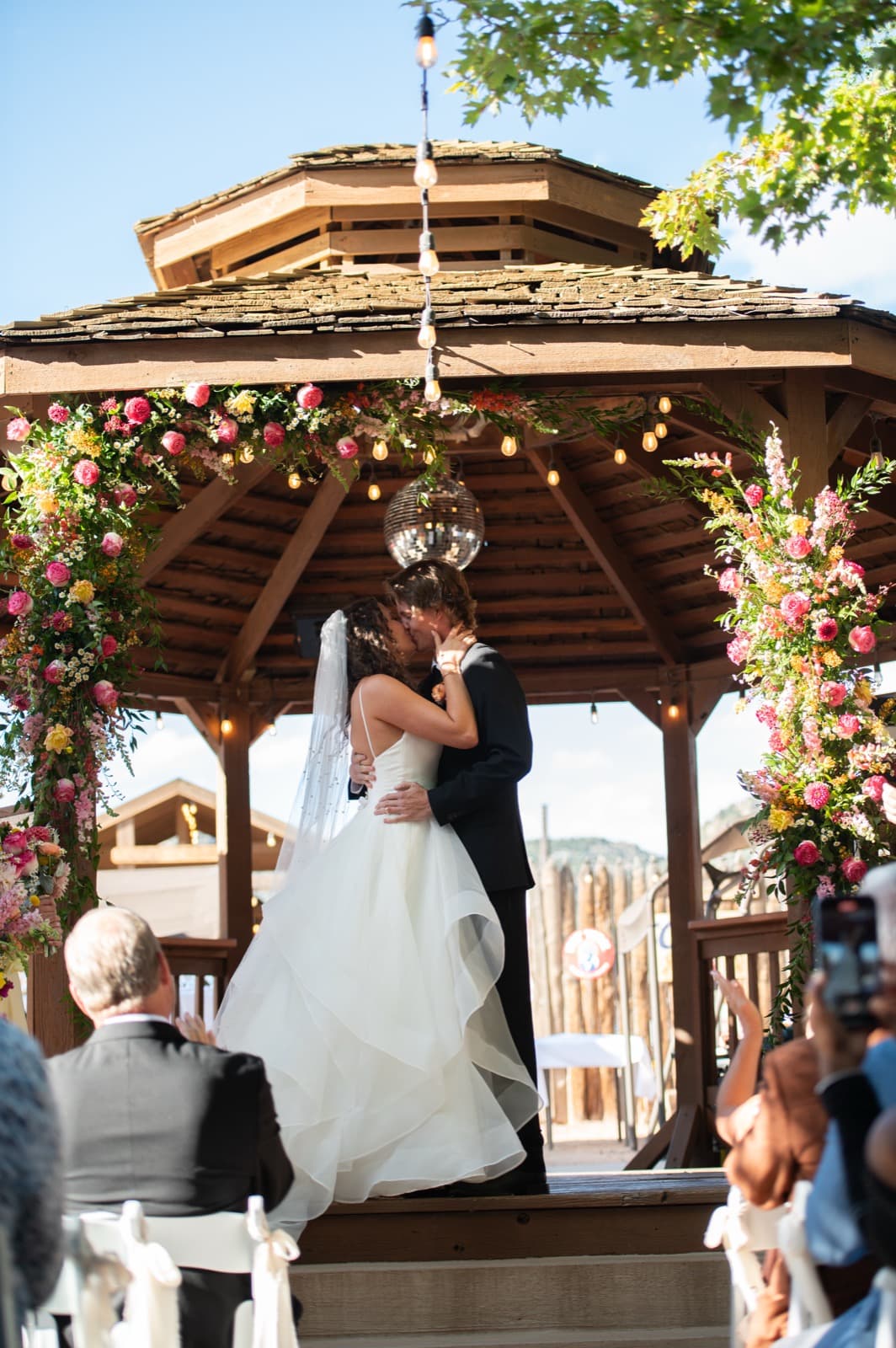 First kiss under the floral arch at an Adventure Beach riverside wedding